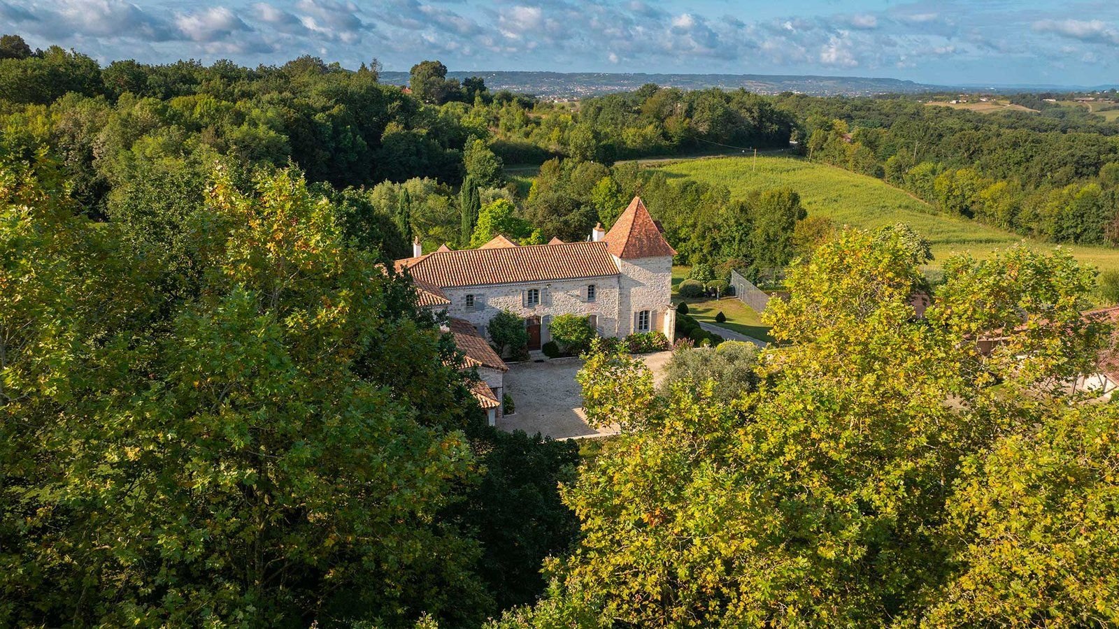 Le manoir au milieu de son parc boisé de quatre hectares, avec la vallée du Lot à l'horizon