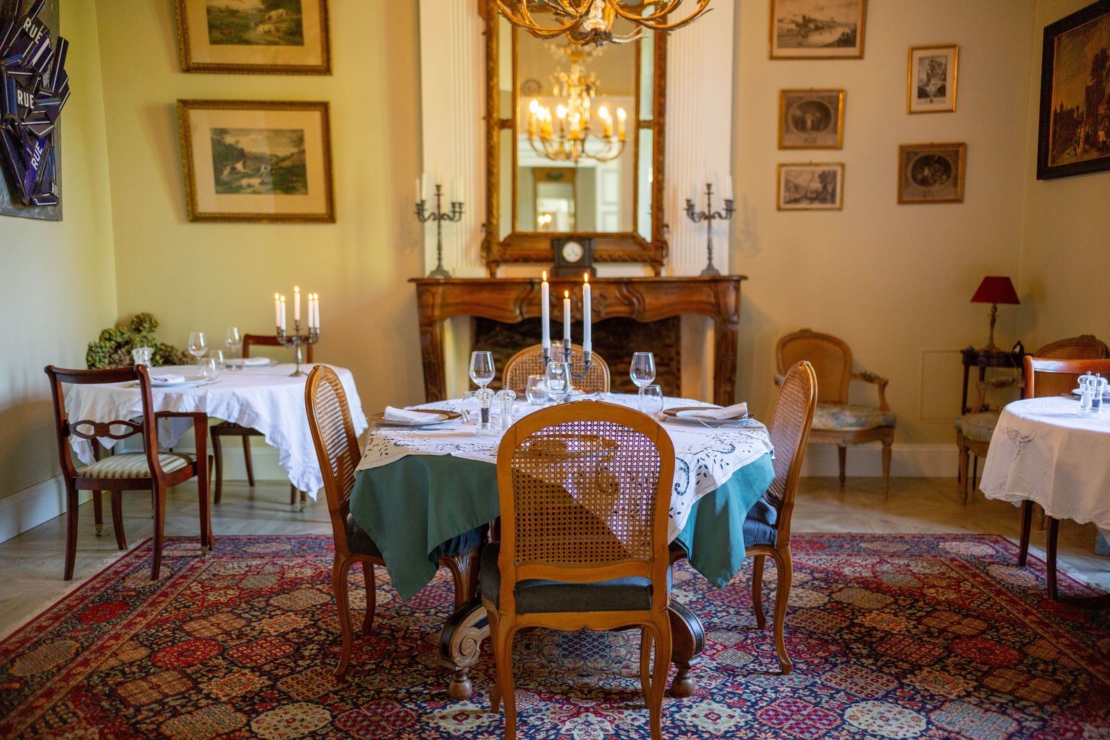 La salle de restauration du manoir : cheminée, lustre et tables dressées